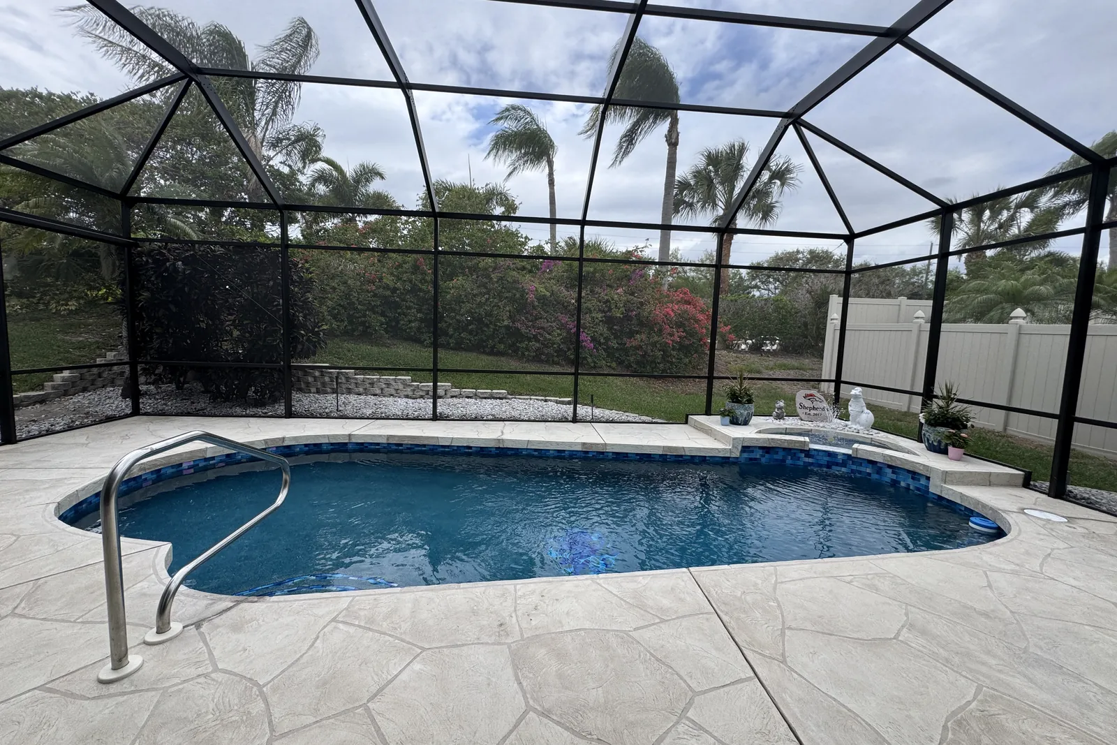 Remodeled pool in Parrish with new finish and glass tile under a screen enclosure