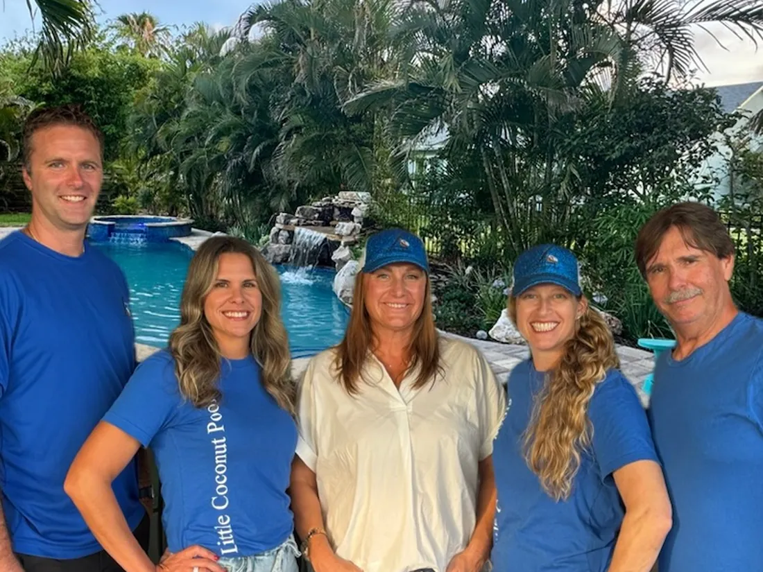 The Little Coconut Pools team standing beside a finished pool with a rock waterfall