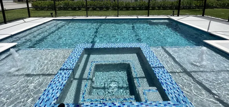 Tiled spa set into a geometric pool under a screen enclosure