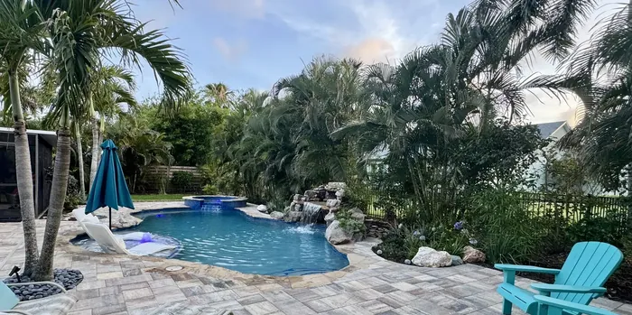 Freeform pool with a raised spa, a rock grotto, palms and a paver deck in Bradenton