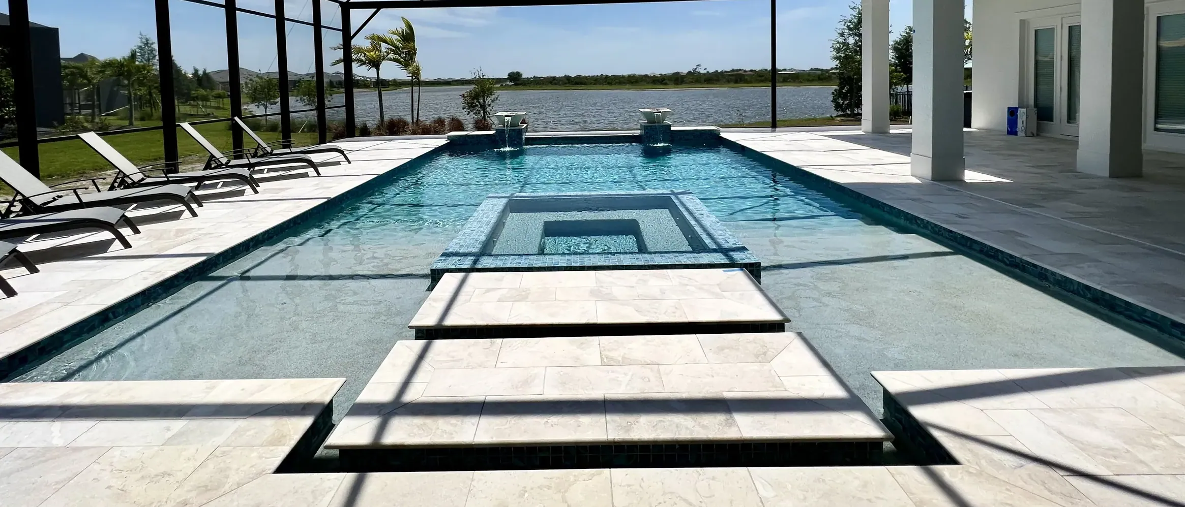 Modern straight line pool with sunken spa. Clearview screen enclosure